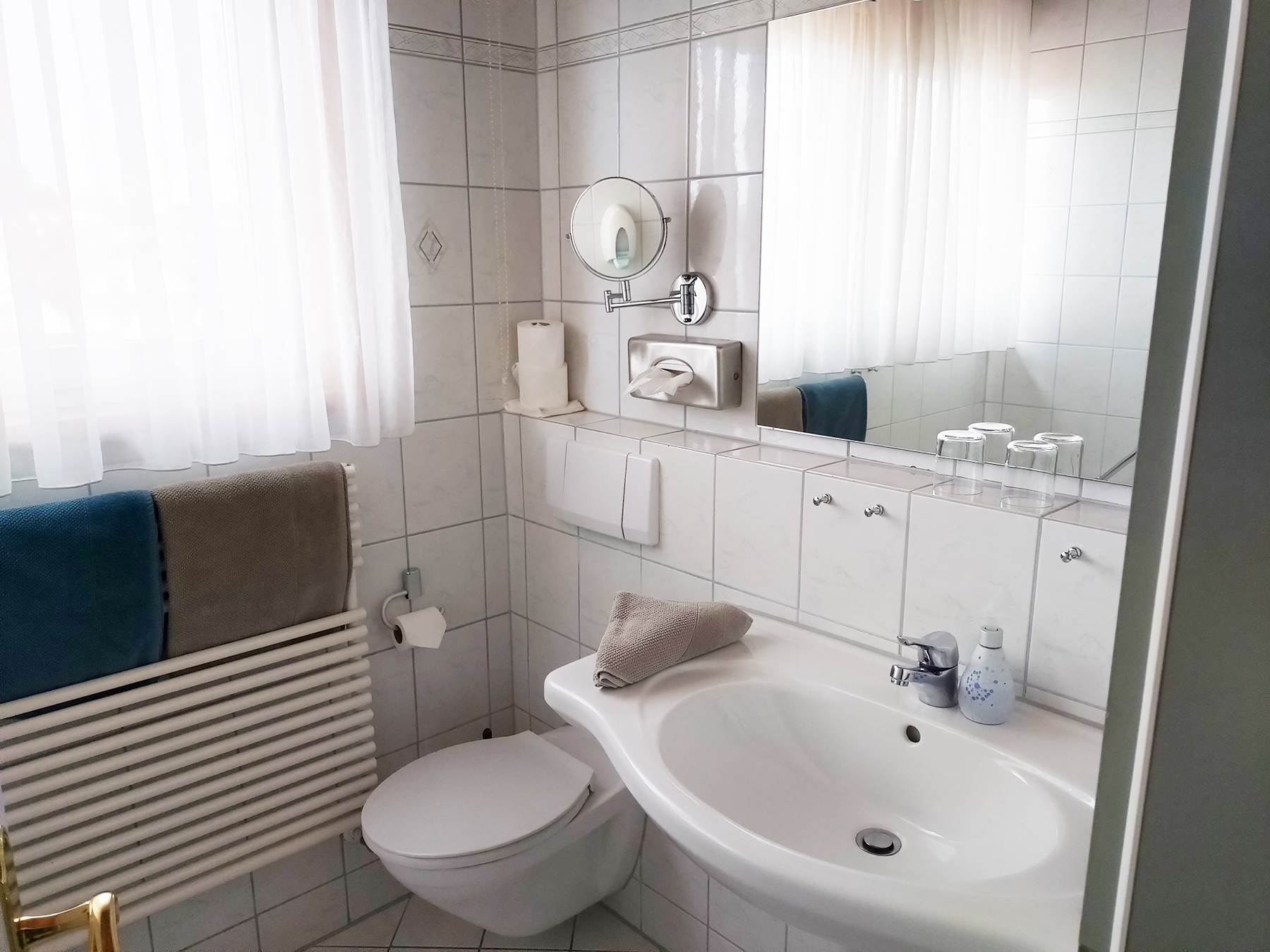 Apartment-Badezimmer mit Dusche, Waschbecken, Spiegel und Handtüchern