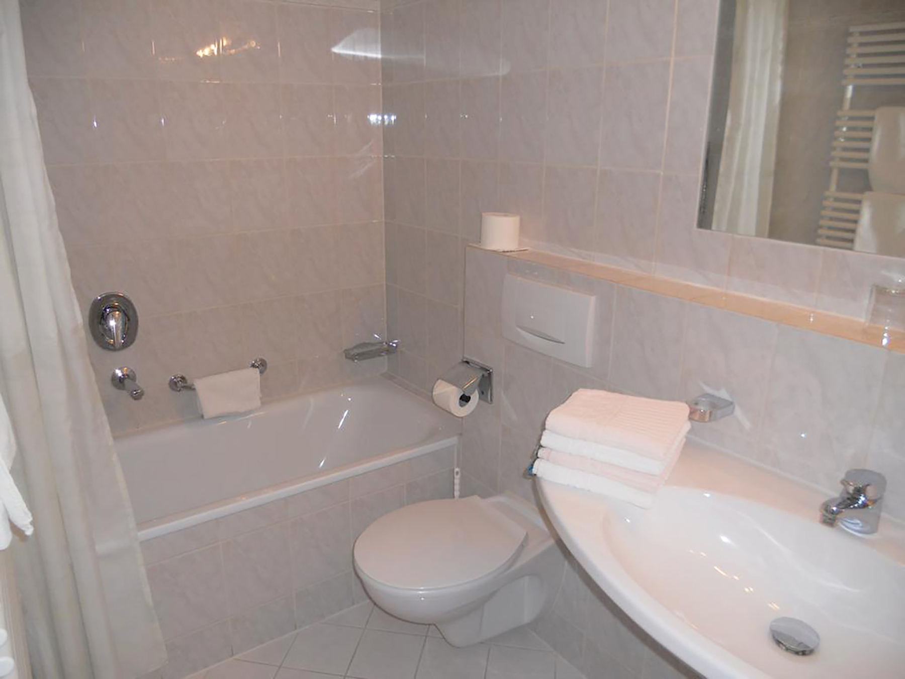 Badezimmer im Doppelzimmer mit Glasdusche, Waschtisch, Spiegel und Handtüchern