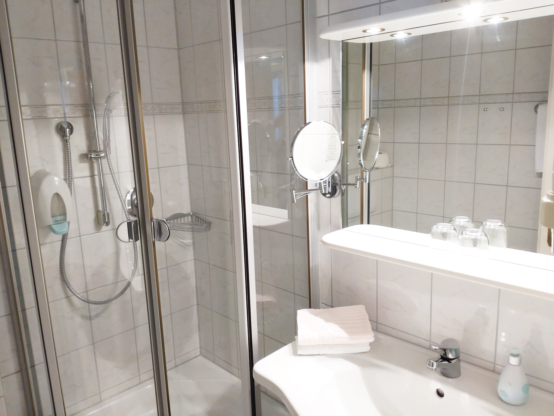 Badezimmer im Ost-Doppelzimmer mit ebenerdiger Glasdusche, Waschbecken und Handtüchern
