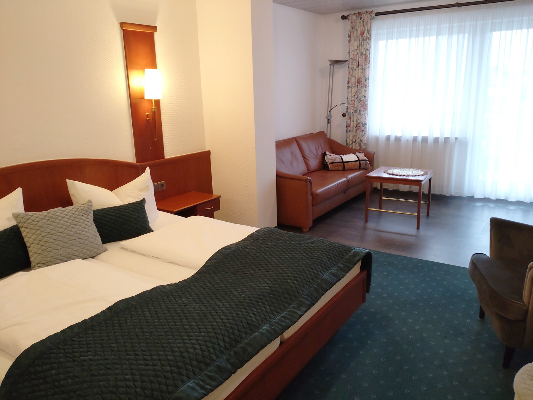 Junior-Suite mit Doppelbett, Sitzecke, Holzboden und großem Fenster